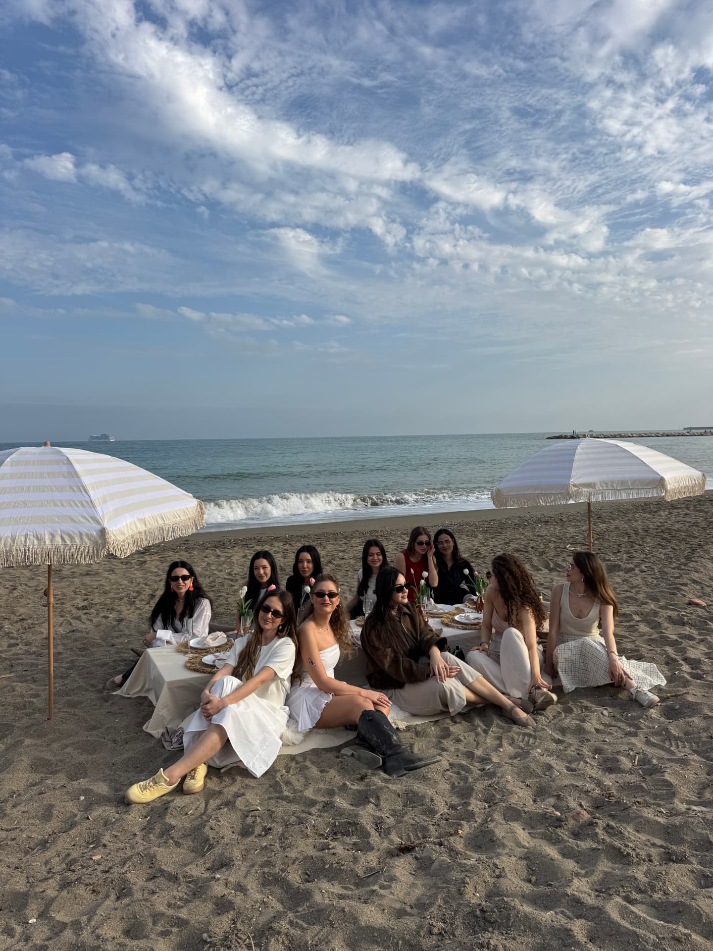 Group of friends celebrating at a styled Boho Tables beach setup on the Costa del Sol